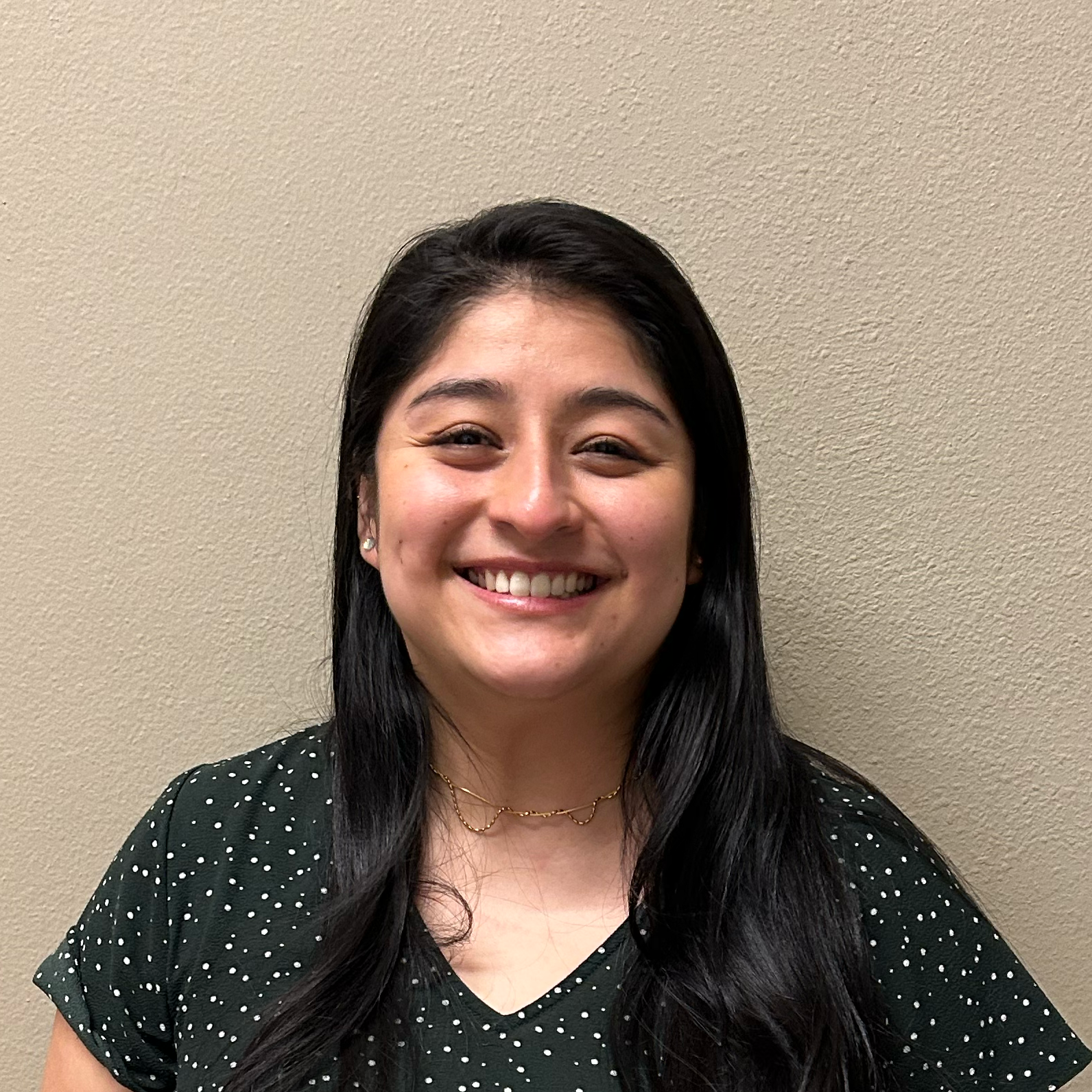Headshot of Fanny Pacheco smiling at the camera, wearing a green shirt with small white polka dots.