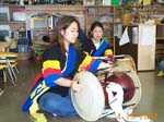 [Korean drummers play with two hands on the wooden Jang-gu drums.]
